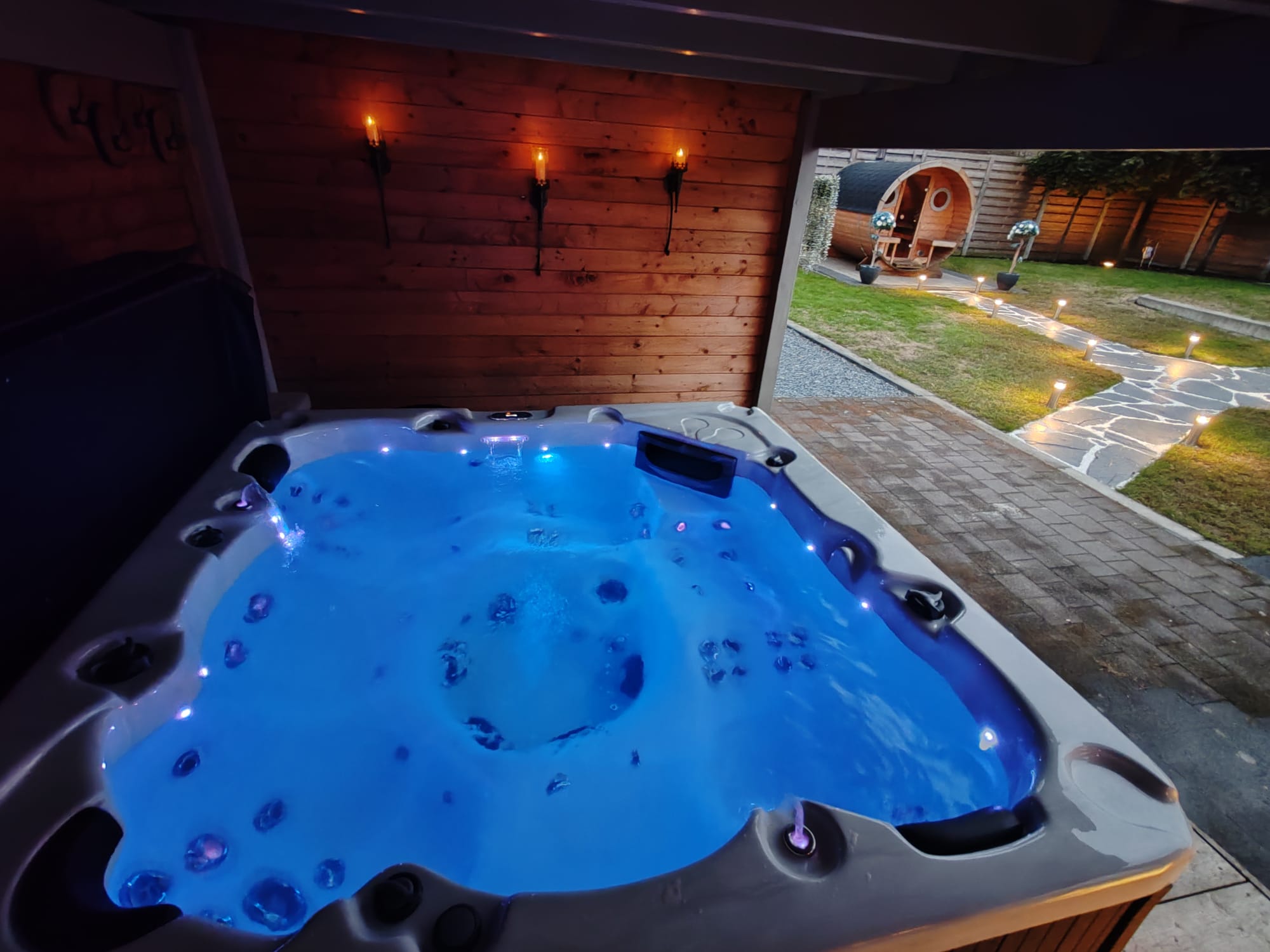 Jacuzzi bij avond met sfeerverlichting en zicht op de tuin